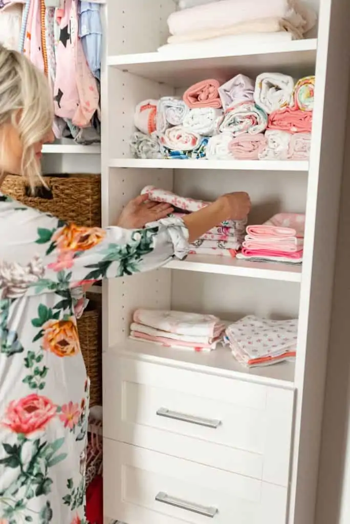 folding and stacking baby clothes in california baby nursery closet